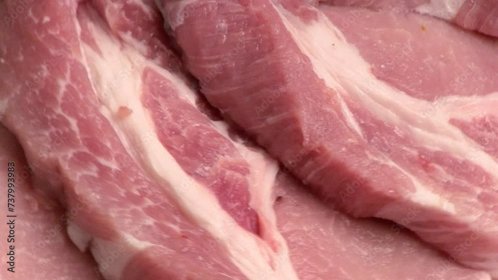 Raw fresh pork meat cut into slices for frying (pork steak) rotating on a kraft wooden board. Zooming the camera from close-up to wide shot. Top view Raw fresh pork meat cut into slices for frying (pork steak) rotating on a kraft wooden board. Zooming the camera from close-up to wide shot. Top view