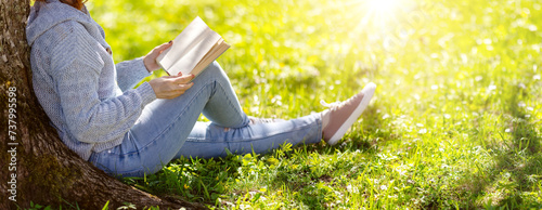 Woman sitting on the blossoming meadow with book in her hands.