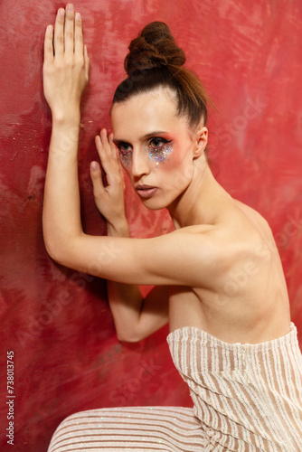 A young woman in a shiny dress on red backgroum nd