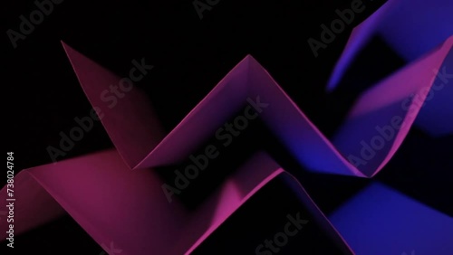 Papel reciclado para  formas de vida sustentables,  doblado en ángulo recto en forma de triángulos, iluminado con luz colorida presenta un  original diseño abstracto y geométrico, con fondo negro. photo