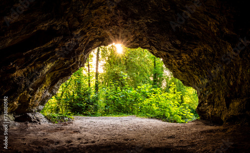 Fototapeta Naklejka Na Ścianę i Meble -  Panoramic view from a small cave (Perick Caves) in a limestone quarry in a nature reserve in Hemer in Sauerland, Germany. Sunlight shines through the lush vegetation inside the cave and illuminates it