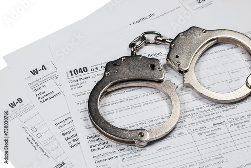 Handcuffs over Tax forms, concepts: Tax fraud or Slave to the Taxes