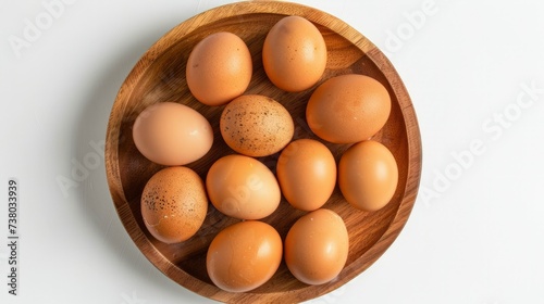 Top view of raw brown eggs on wooden plate isolated on white background. Eggs are a common ingredient in cooking.