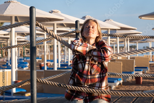 Young Woman sitting on a pier in sunrise, enjoying the view