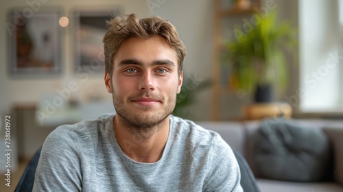 A young man sits in a chair at a consultation with a psychotherapist. He looks at the camera smiling