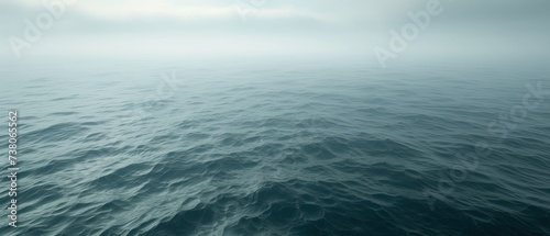 a large body of water with waves in the foreground and a few clouds in the sky over the water. photo
