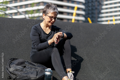 Mature woman enjoy outdoor fitness, use watch, and preparing for a run.