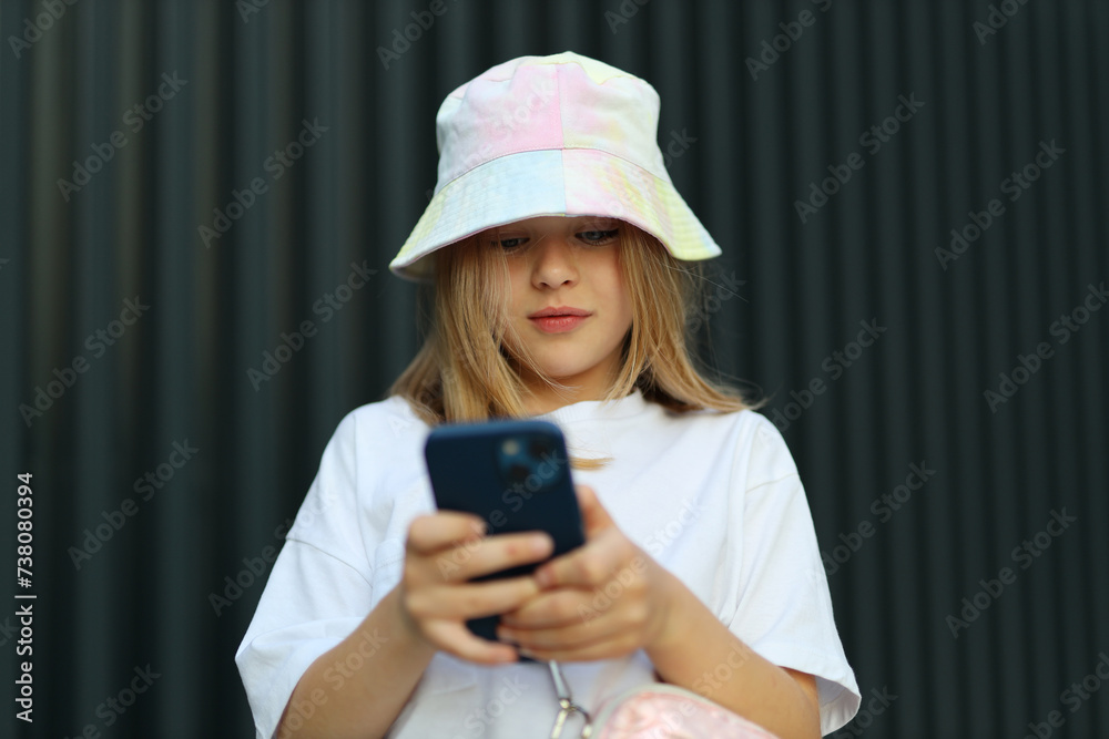 A young children girl embraces city life, using her smartphone outdoors in the summer streets. A young children girl embraces city life, using her smartphone outdoors in the summer streets.