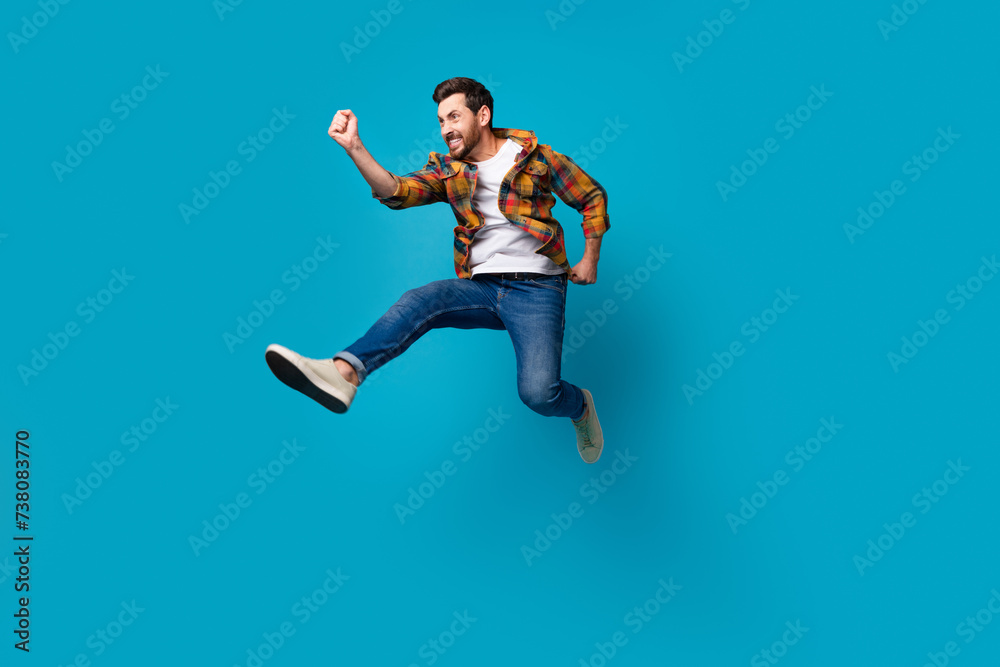 Fototapeta premium Full size photo of handsome young male running fast shopping promo dressed stylish checkered outfit isolated on blue color background