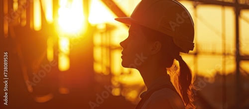 At sunset, a female engineer dons a safety helmet on her head.