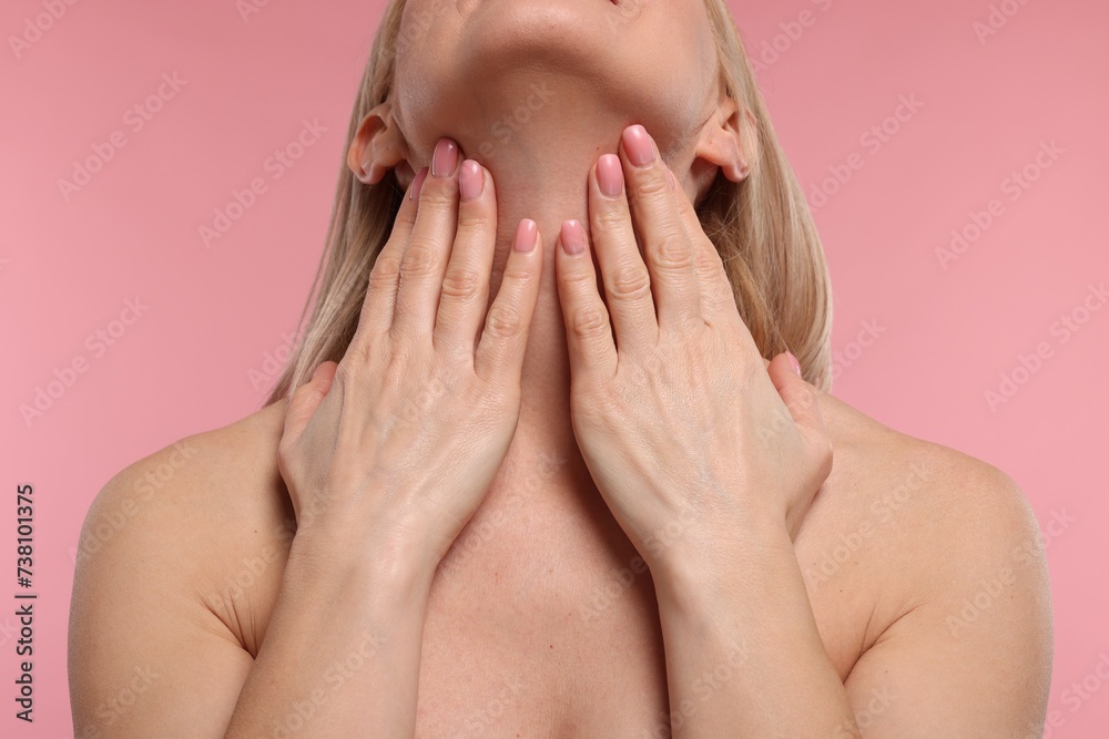 Fototapeta premium Woman touching her neck on pink background, closeup
