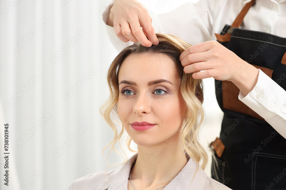 Fototapeta premium Hair styling. Professional hairdresser working with client in salon, closeup. Space for text