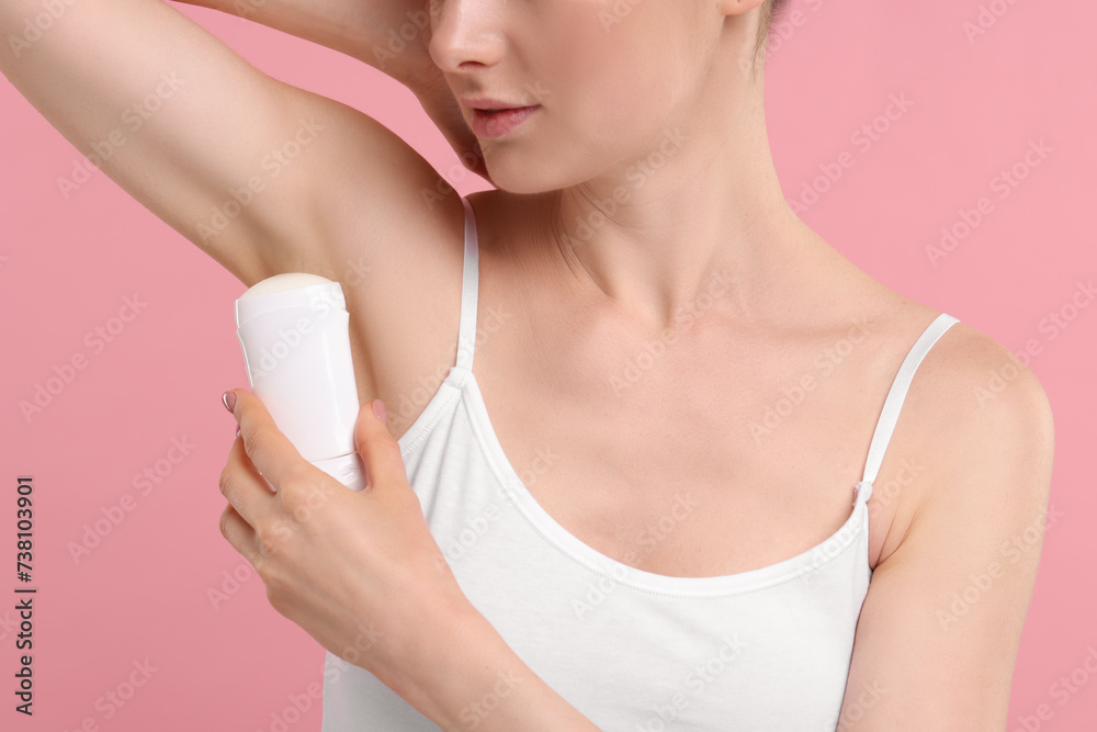 Woman applying deodorant on pink background, closeup Woman applying deodorant on pink background, closeup
