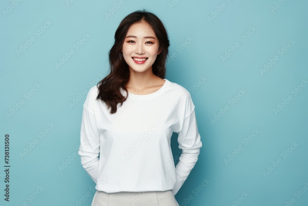 Smiling young woman in a plain white t-shirt posing against a soft blue background. Smiling young woman in a plain white t-shirt posing against a soft blue background.