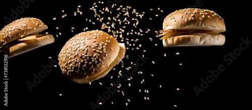 Flying burger buns with sesame seeds on black background.