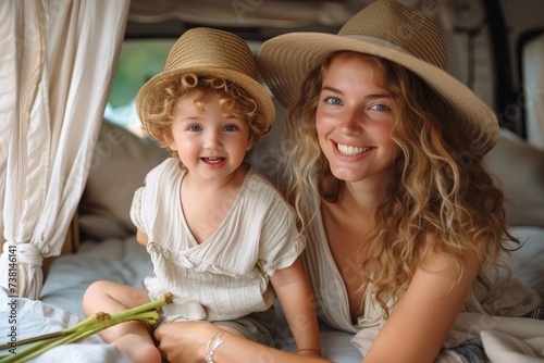 Mother and child with hats smiling and holding flowers inside camper photo