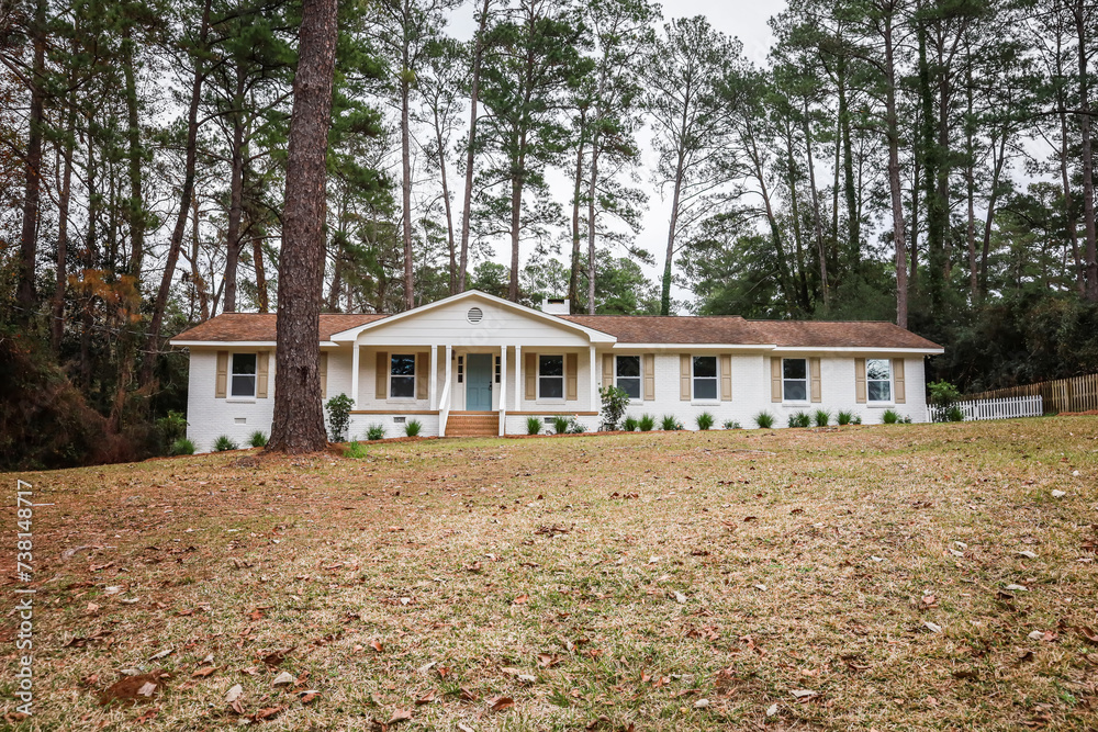 The front exterior entrance of a newly painted white siding brick ranch style house with a large yard that has been recently renovated The front exterior entrance of a newly painted white siding brick ranch style house with a large yard that has been recently renovated