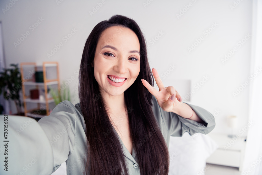 Photo portrait of attractive young woman toothy selfie photo show v-sign wear trendy gray pajama isolated on white modern interior design