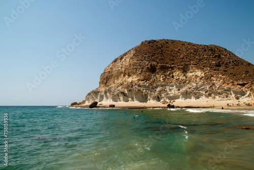 Bañistas en la cala de Enmedio, cabo de Gata, Agua Amarga, Almería, España. Pequeña playa rodeada de terreno escarpado erosionado por el mar Mediterráneo. photo