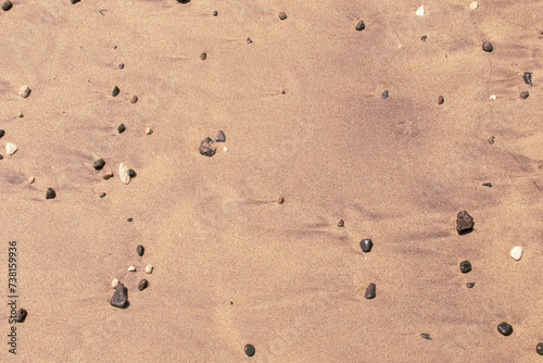 Arena mojada tras el reflujo de la ola en la playa. Arena y pequeños cantos rodados arrastrado por la marea en la cala de Enmedio en Níjar, Almería, España.