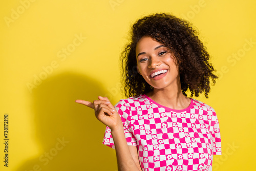 Photo of friendly lovely girl toothy smile direct finger empty space novelty isolated on yellow color background