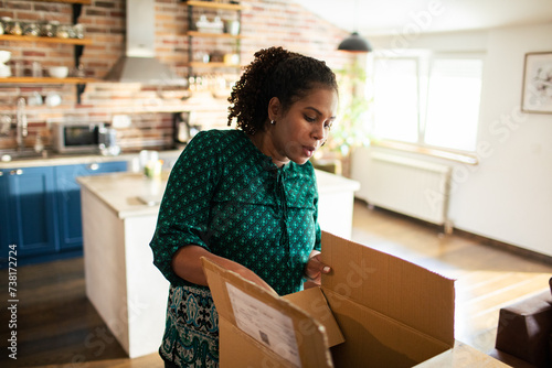 Woman opening cardboard box shipment at home photo