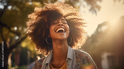 A young African American woman with short hair is seen dancing and laughing in a public park during springtime - black girl wearing casual clothes, exuding joy, liveliness, and youthfulness photo