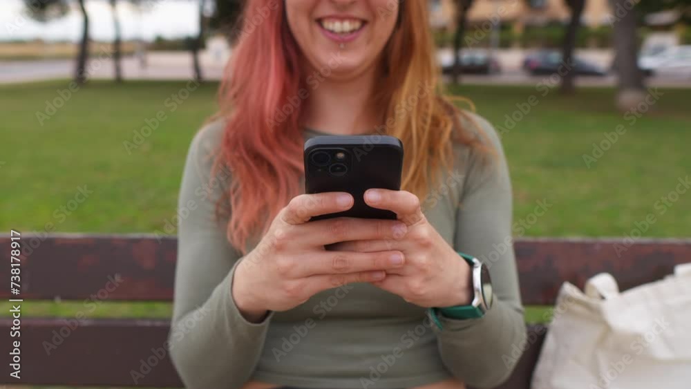 Smiling woman texting on her phone, seated on a park bench Smiling woman texting on her phone, seated on a park bench