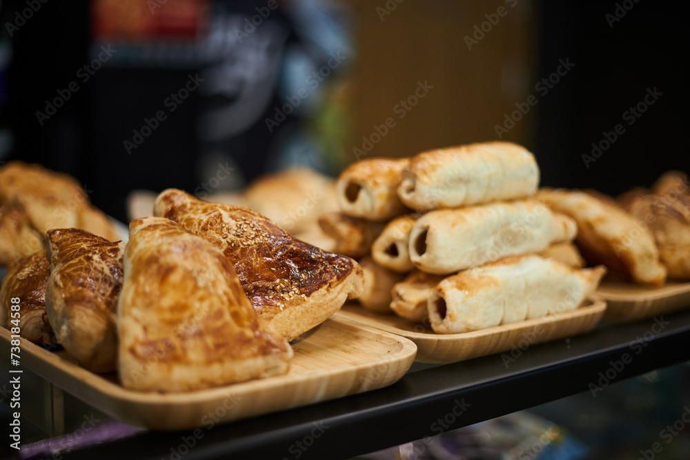 Samsa, sausages in dough, kurnik. Varied selection of pastries and snacks in coffee shop. Bakery delicious food background, buffet catering. Golden puff pastry baked in the oven. Samsa, sausages in dough, kurnik. Varied selection of pastries and snacks in coffee shop. Bakery delicious food background, buffet catering. Golden puff pastry baked in the oven.