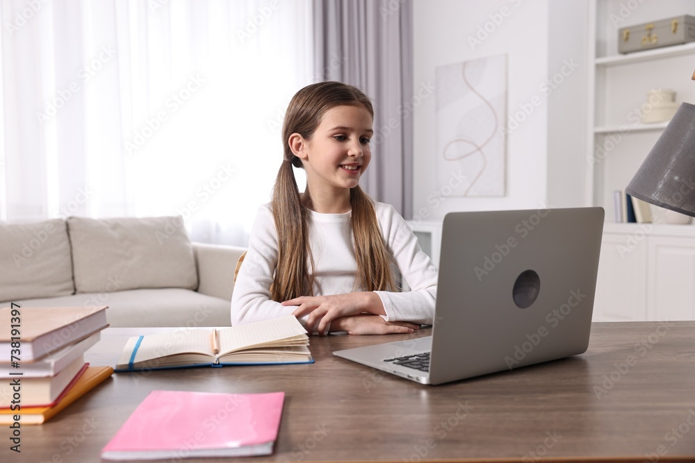 E-learning. Cute girl using laptop during online lesson at table indoors E-learning. Cute girl using laptop during online lesson at table indoors