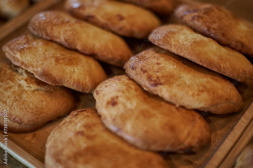 Fresh pastries lie in two rows on a wooden plate. Sweetish Bakery pastry snack. Sochnik - Russian curd cake baked in the oven. Sochen sweet made from shortcrust pastry with cottage cheese filling