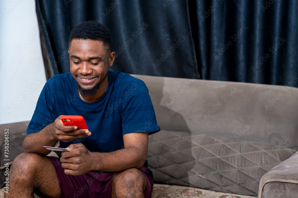 young african man using mobile phone and card young african man using mobile phone and card