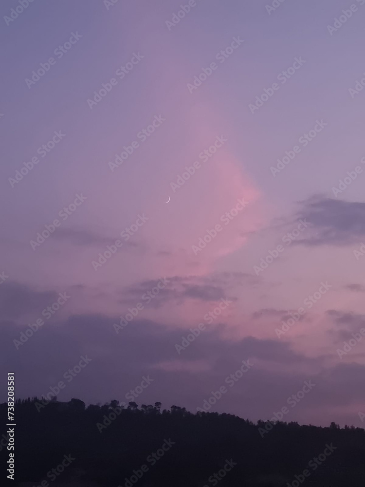 The image shows a breathtaking view of a rural landscape at dusk, with a stunning purple sky adorned with wispy clouds. The sky is reflected in a tranquil body of water, creating a picturesque scene. 