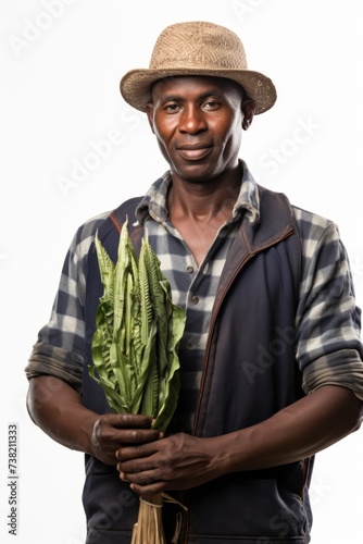Portrait of a smiling African male farmer holding a bunch of green vegetables