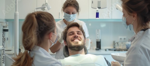 Dental examination being provided to a handsome man with dentist and assistant present.
