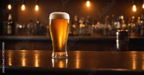  Golden beer with foam on a wooden bar table with lights in the background