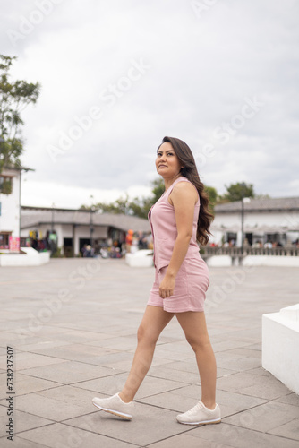 beautiful young woman with long hair and wearing a pink dress, latin model beauty and fashion, lifestyle of tourist exploring the city in the day © Alejandro