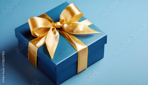 Stylish Blue Gift Box with a Golden Bow on a Blue Background for Father's Day with copyspace