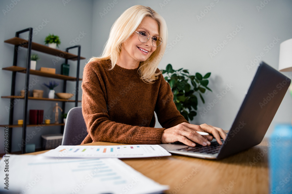 Close up photo of pensioner blonde hair business woman calculating her pension using netbook at workstation indoors office location Close up photo of pensioner blonde hair business woman calculating her pension using netbook at workstation indoors office location