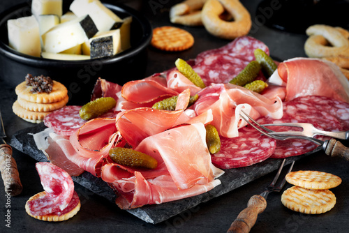 Meat platter with cold cuts of speck and salami, served with pickles, crackers and taralli