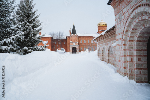 a snowy path leading to a brick building with a tower in the background