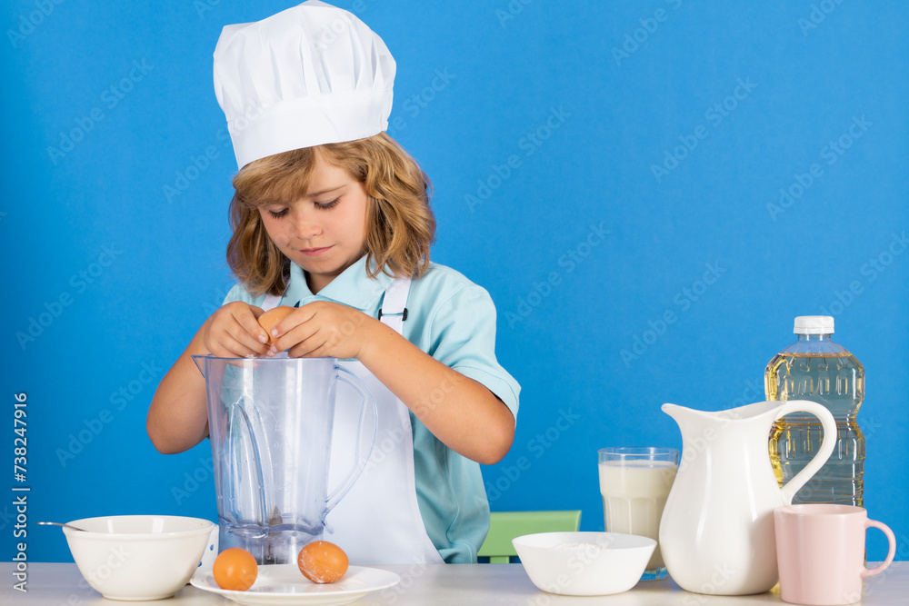 Child wearing cooker uniform and chef hat preparing vegetables on kitchen, studio portrait. Cooking, culinary and kids food concept. Child wearing cooker uniform and chef hat preparing vegetables on kitchen, studio portrait. Cooking, culinary and kids food concept.