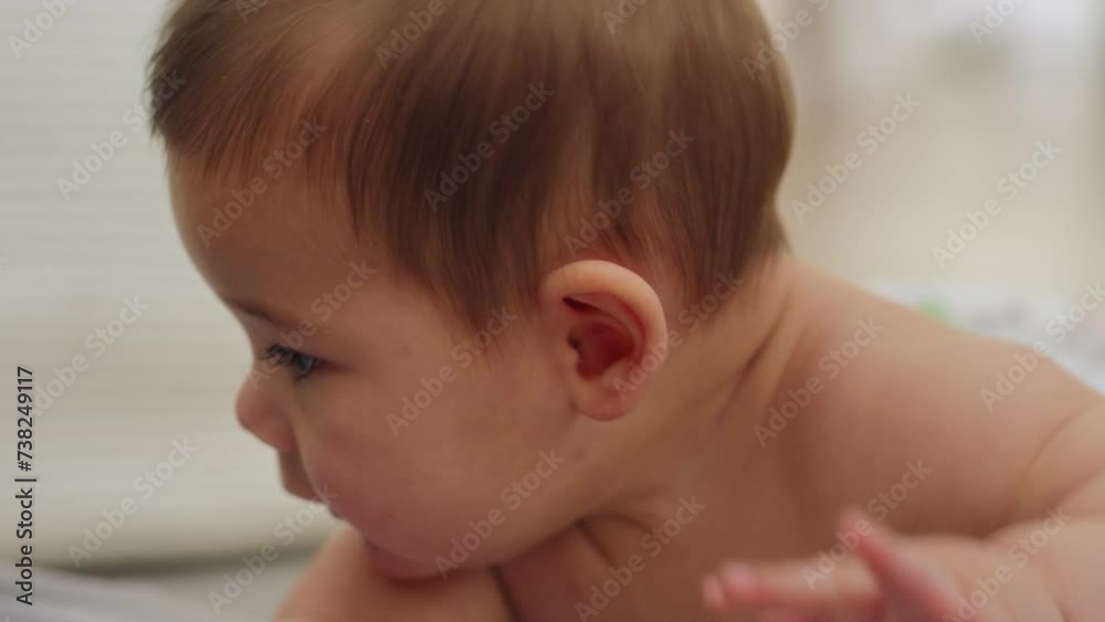 Baby boy playing around on the floor shirtless looking at the camera. Closeup shot of baby's face Baby boy playing around on the floor shirtless looking at the camera. Closeup shot of baby's face