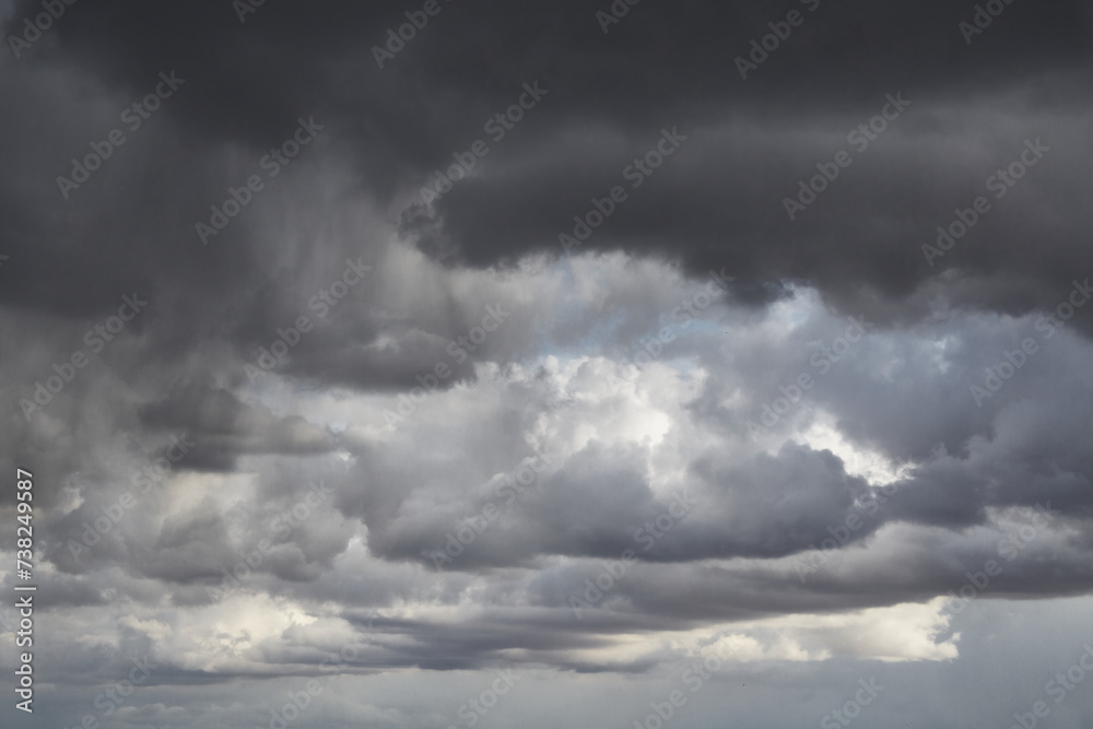Grey storm clouds on a blue sky, rays of light on grey clouds Grey storm clouds on a blue sky, rays of light on grey clouds