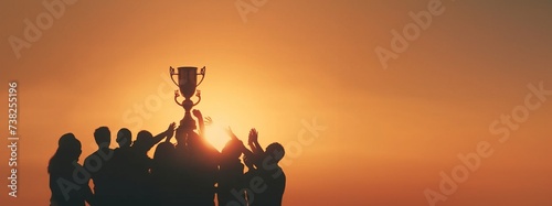 Winning team is holding trophy in hands. Silhouettes of many hands in sunset