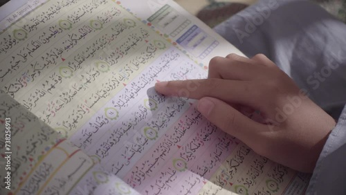 The Colour-Coded Quran for Easy Tajweed and Memorization is being reading with the finger photo