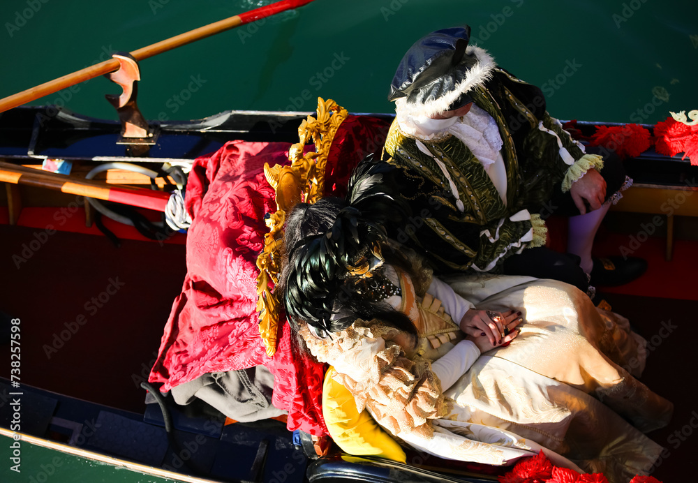 Venice, VE, Italy - February 13, 2024: married couple with historical costumes on the gondola during the carnival - obrazy, fototapety, plakaty 