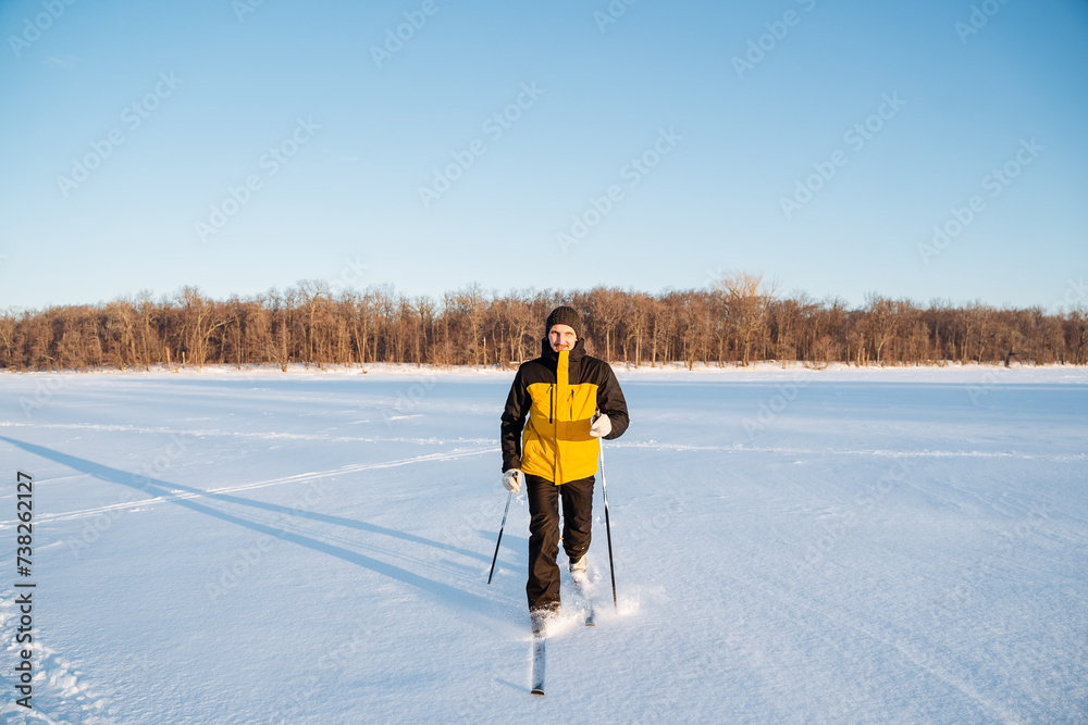 Man training on skis, running on snow field, solo walk in the fresh air.
