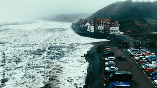 Stormy winter scene. Rough seas of the English coast with mist and fog. Aerial footage of the sleepy coastal town of Sandsend beach on the coast of north Yorkshire in England photo