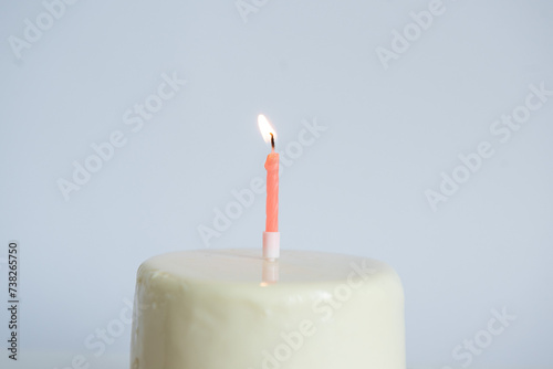 White mini birthday cake with one candle.